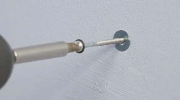 A molly bolt is tightened with a wrench