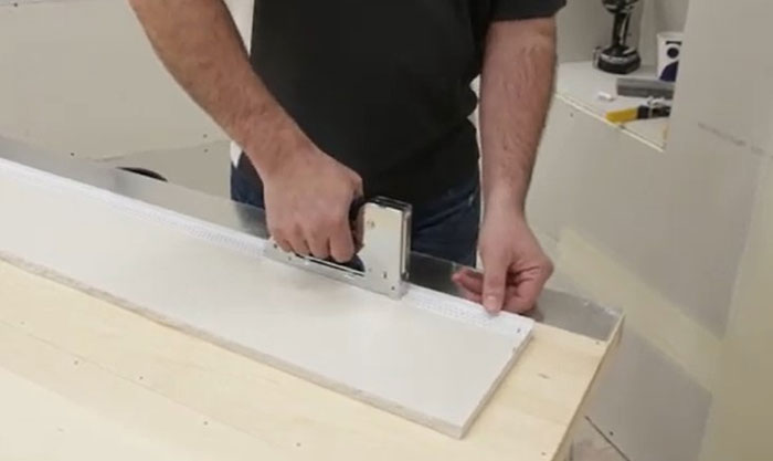 A person using a staple gun to install drywall