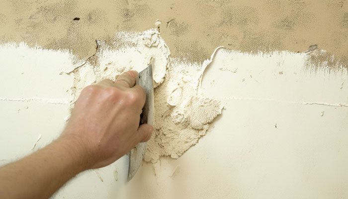 Applying mud to torn drywall paper to fill in and smooth the surface